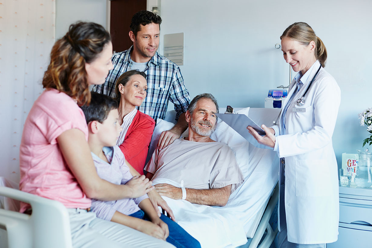 man in hospital bed with family, speaking to doctor