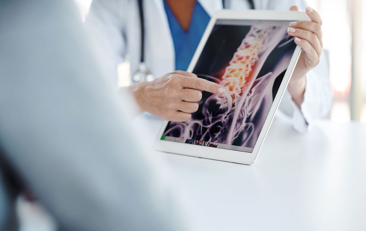 person's finger pointing at computer image of spine