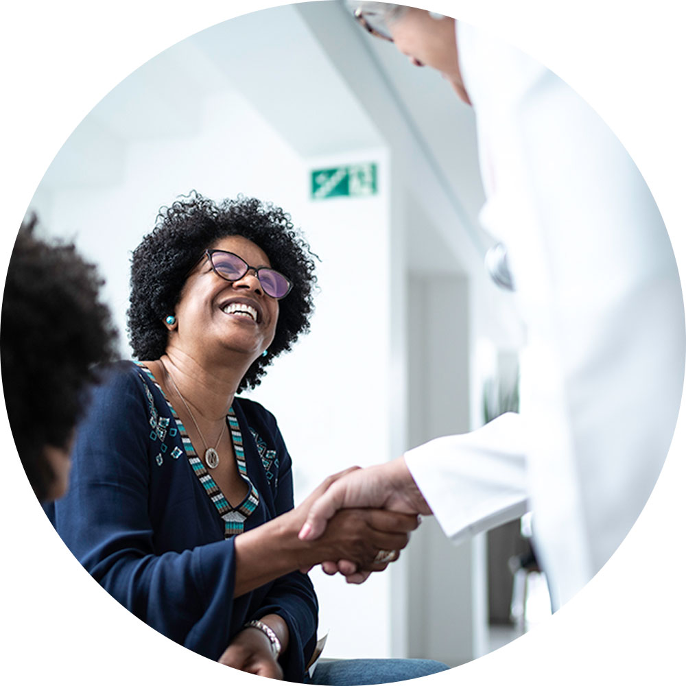 Black woman smiling and shaking hands with doctor