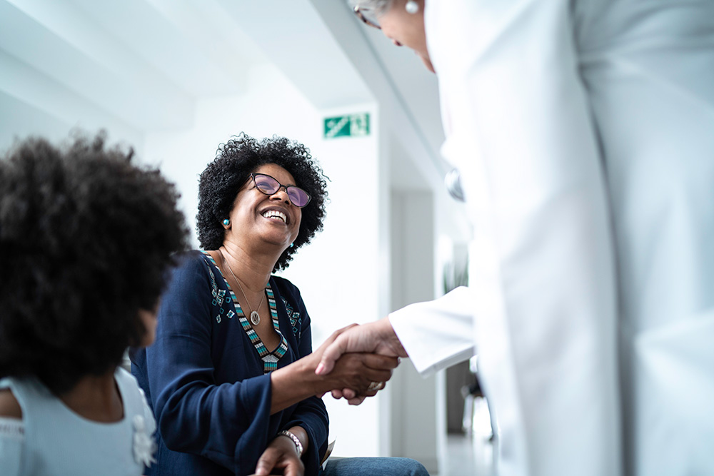 Black woman smiling and shaking hands with doctor